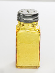 Salero amarillo con sal sobre fondo blanco