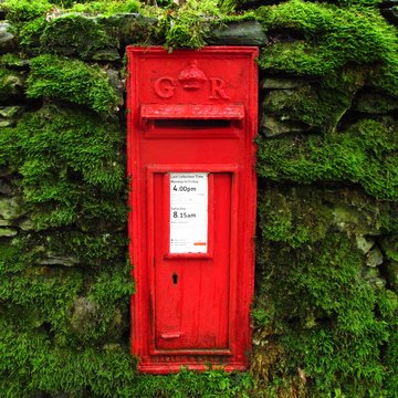 old-fashioned British mailbox postbox letterbox embedded in mossy wall