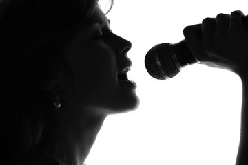 silhouette of a woman singing with a microphone in hands