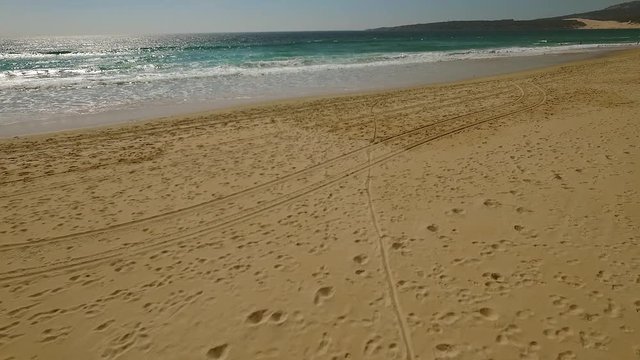 Young woman walking alone along a deserted sandy tropical beach enjoying the tranquility of nature  high angle distance view
