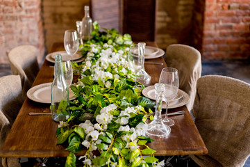тарелки с ножом и вилкой и бокалами на деревянный стол, украшенный искусственными цветами