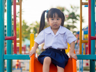 Happy kid, asian baby child in school uniform playing on playgro
