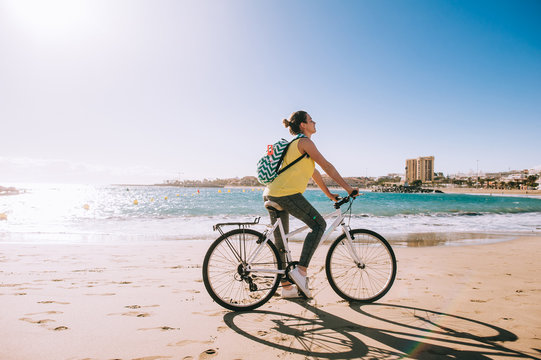 carefree woman with bicycle riding on beach sand having fun and
