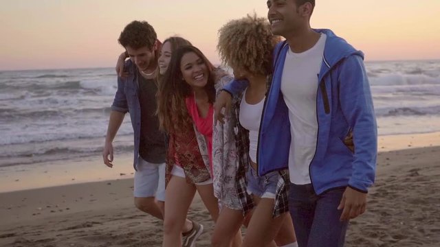 Sexy young attractive people walking down the sandy beach in the evening and have a great time in slow motion.