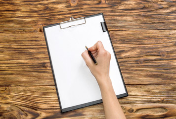 woman writing on a blank sheet on a clipboard