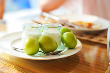  Cup of yogurt on table with green fruits.