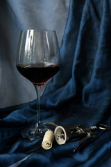 a glass of wine, a corkscrew and stopper