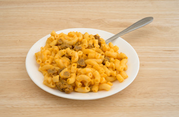 Mac and cheese with burger on plate with fork atop a wood table top side view