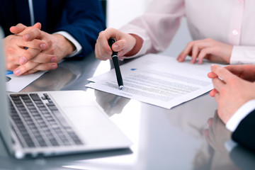Group of business people and lawyers discussing contract papers sitting at the table, close up