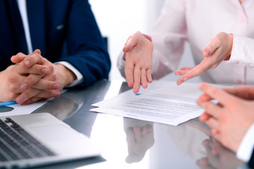 Group of business people and lawyers discussing contract papers sitting at the table, close up