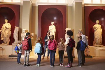 Pupils And Teacher On School Field Trip To Museum With Guide - obrazy, fototapety, plakaty