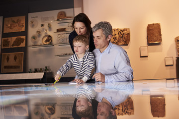 Family On Trip To Museum Looking At Map Together