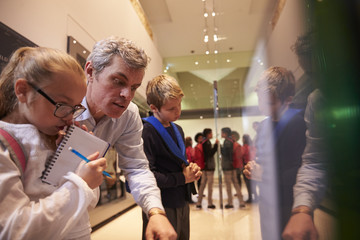 Teacher And Pupils Looking At Artifacts On Display In Museum