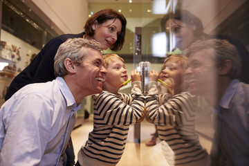 Family Looking At Artifacts In Glass Case On Trip To Museum - obrazy, fototapety, plakaty