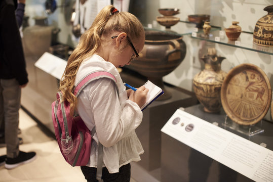 Student Looking At Artifacts In Case On Trip To Museum