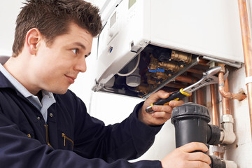 Male Plumber Working On Central Heating Boiler