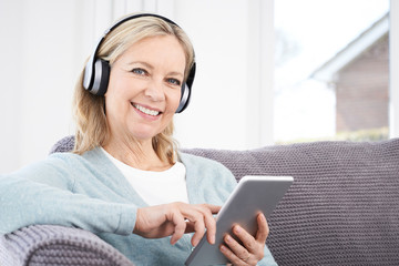 Mature Woman Streams Music From Digital Tablet To Wireless Headp
