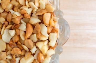 Macadamia nut pieces in a glass bowl on wood table