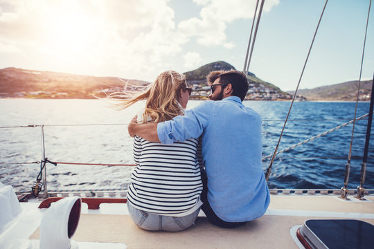 Rear view of young couple sitting on yacht deck