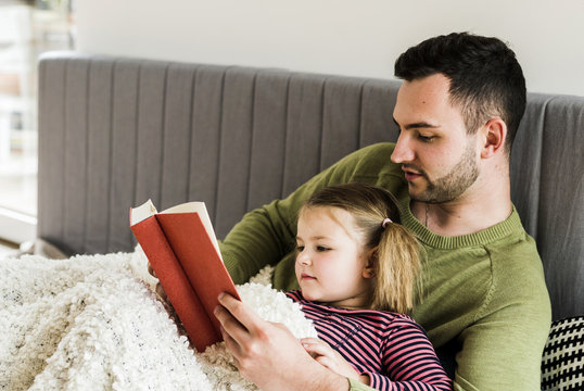 Father and daughter reading a book at home