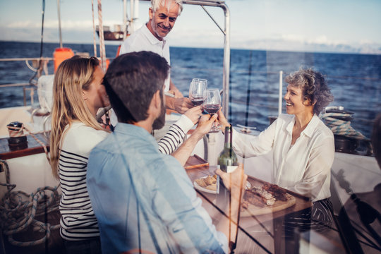 Senior and young couple on a yacht toasting wine