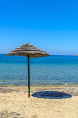 Beautiful sandy beach in Syros, Cyclades, Greece. Straw umbrella