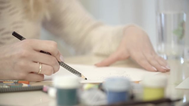 The girl draws pencil sketch on paper. Close-up slow motion footage.