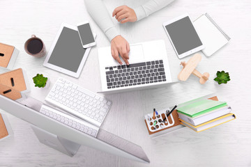 Concept of using electronics. Businesswoman works at office. Computer, laptop, tablet, cup of coffee and other things on the table. Top view