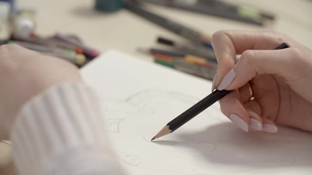 Girl Drawing a Picture With Pencil. The girl draws pencil sketch on paper. Close-up slow motion footage.