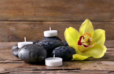 Fototapeta na wymiar Spa still life with stones, flower and candlelight on wooden background