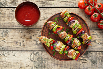 Fototapeta na wymiar Roasted turkey or chicken meat shish kebab skewers with ketchup sauce, chopped parsley and tomatoes on rustic wooden table background. Traditional barbecue grill food
