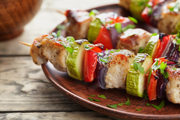 Grilled marinated turkey or chicken meat shish kebab skewers with ketchup sauce, chopped parsley and tomatoes on rustic wooden table background. Traditional barbecue grill food