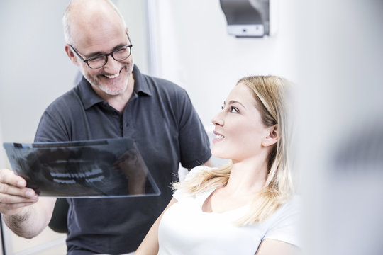 Dentist showing x-ray image to patient, sitting in dentist's chair