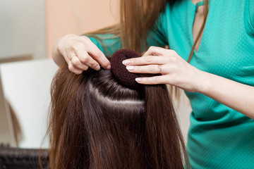 Fototapeta premium Hairdresser make evening hairstyle on brown hair in beauty salon.