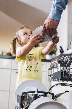 Daughter helping father clearing dishwasher