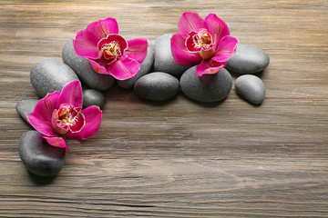 Stones and red orchid on wooden background
