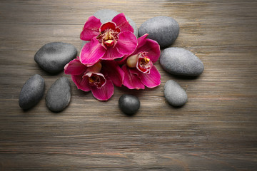 Fototapeta na wymiar Stones and red orchid on wooden background