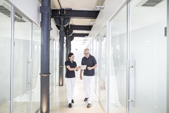 Two dentists using digital tablet in corridor