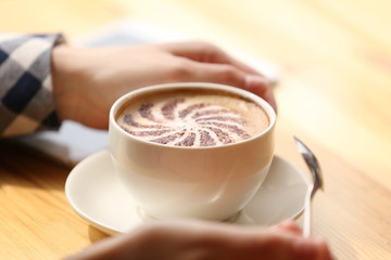 Female hands holding cup of coffee with foam, closeup