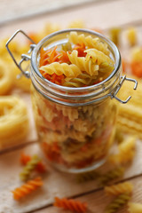 Fusilli pasta in a jar on wooden table background