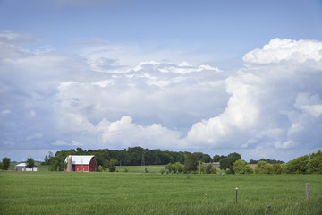 Obraz premium Red barn and field below dramatic cloudscape