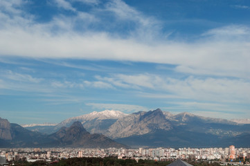 Fototapeta na wymiar City and mountains background. Sunny landscape with blue sky