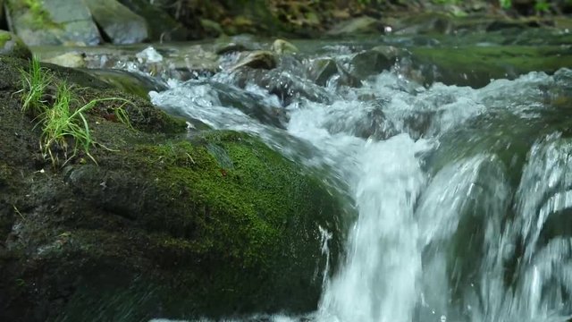 Small stone waterfall on a stream in the mountains. Relaxing sound of water.

