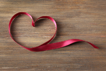 Red heart shaped ribbon on wooden background