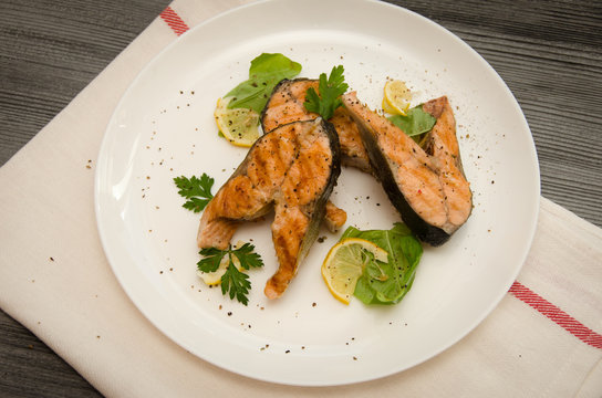 several salmon steaks white round plate spices