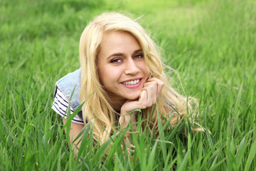Naklejka na ściany i meble Young beautiful woman on green grass