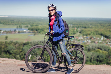 Naklejka premium Beautiful sensuality elegance traveler woman cyclist, has happy fun cheerful smiling face, ripped blue jeans. Has slim sport body.