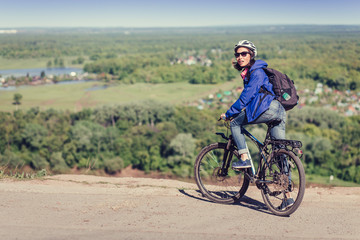 Thoughtful young woman with helmet riding bike in forest