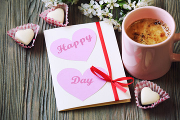 Cup of fresh coffee and card on wooden background