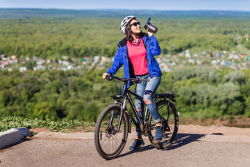 Obraz premium Sport young woman drinking water after doing some bicycle exerci